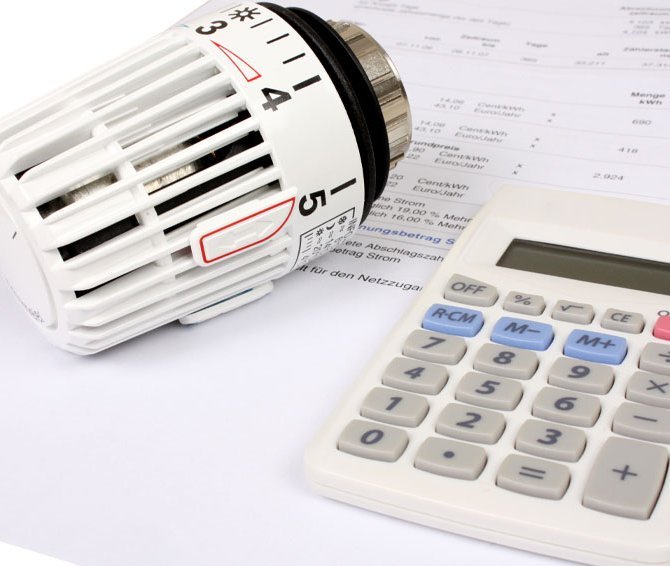 Ein Taschenrechner und ein Thermostat liegen auf einer Rechnung.